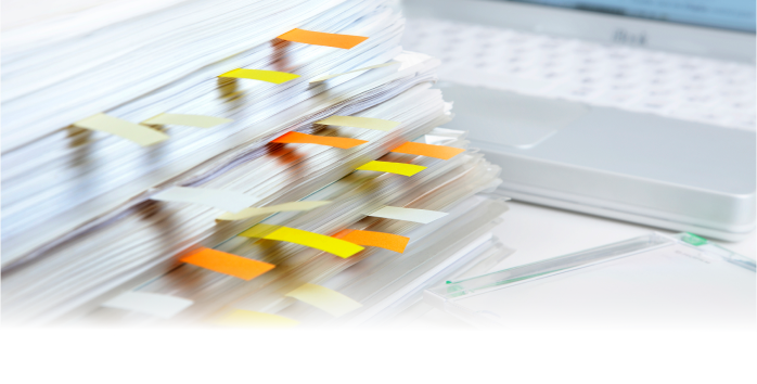 付箋がついた書類がデスクの上に重なっている様子